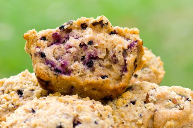 An elderberry muffin half sitting on top of a pile of other muffins