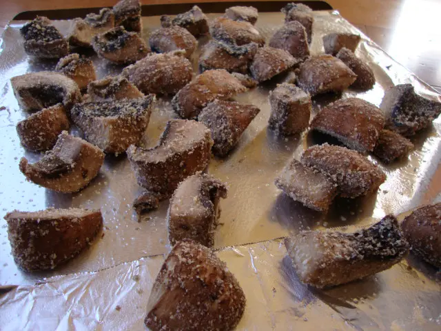 Breaded portobello pieces on a baking sheet covered with foil.