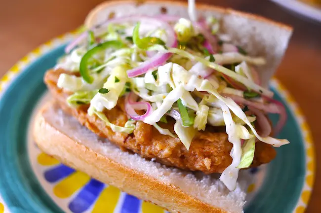 A bun has a fried chicken patty and slaw on top.