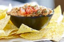 Corn tortilla chips surround a bowl of hummus prepared with southwestern spices