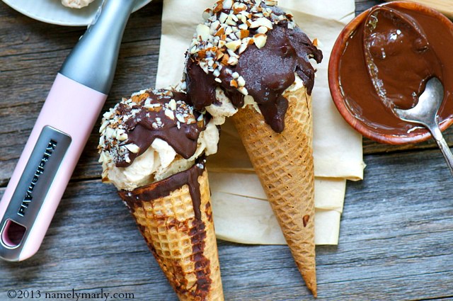 Two vegan drumstick cones sit next to melted chocolate and an ice cream scoop.