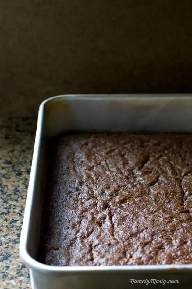 The brownie layer in a baking dish, sitting on a counter.