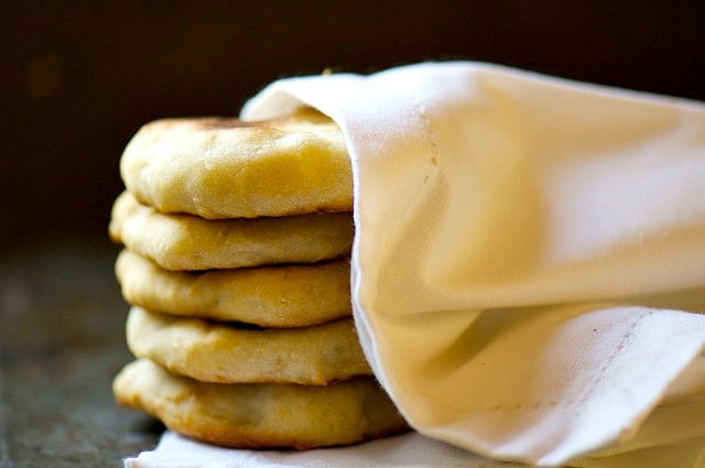 A stack of vegan naan bread has a kitchen towel wrapped around it.