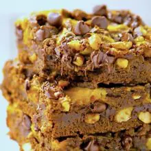 A stack of pumpkin swirl brownies shows lots of melty chocolate chips and nuts on top.