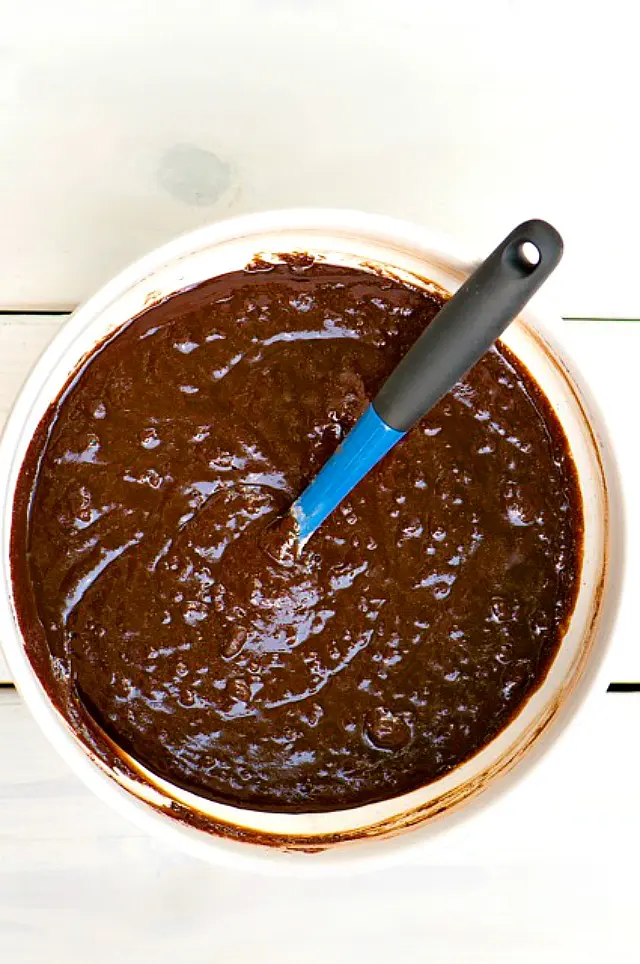 Looking down on a mixing bowl full of chocolate batter with a blue spatula.