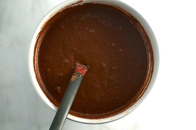 chocolate Cake batter in a bowl with a red and grey spatula.