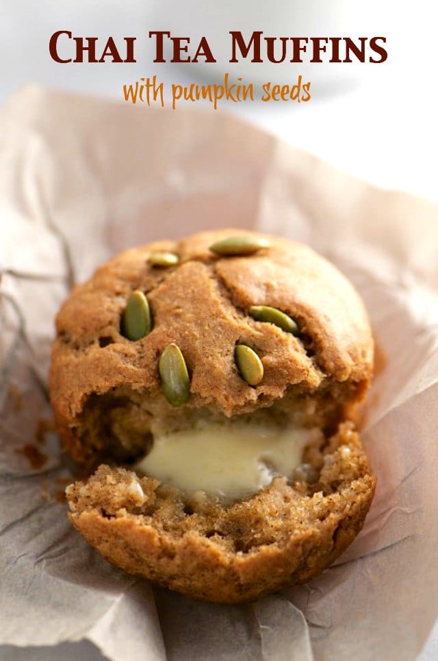 A muffin sits on a white paper. It's torn in half and a bit of melted butter is inside. The text at the top reads: Chai Tea Muffins with Pumpkin Seeds 