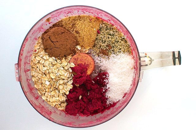 Ingredients are in a food processor, including oats, coconut flakes, and more.