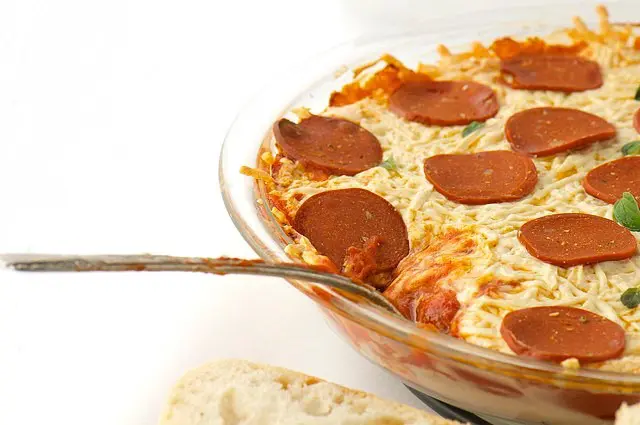 A spoon rests inside a dish full of vegan pizza dip.