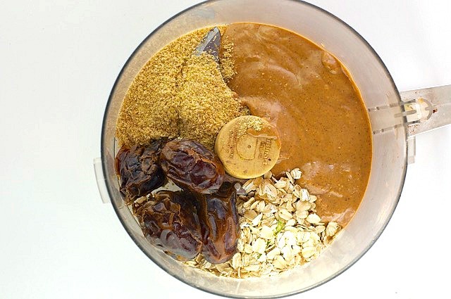 Looking down on a food processor bowl full of peanut butter, dates, oatmeal, and more.