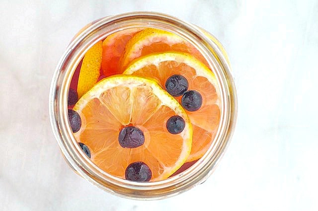 Looking down on a mason jar with fruit punch, orange slices, and berries.
