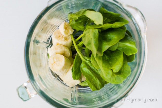A close-up look at a blender jar full of sliced bananas and fresh spinach.