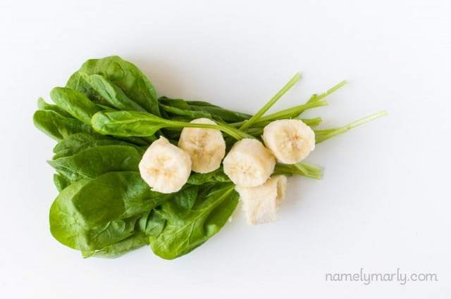 Looking down on fresh spinach leaves topped with sliced bananas.