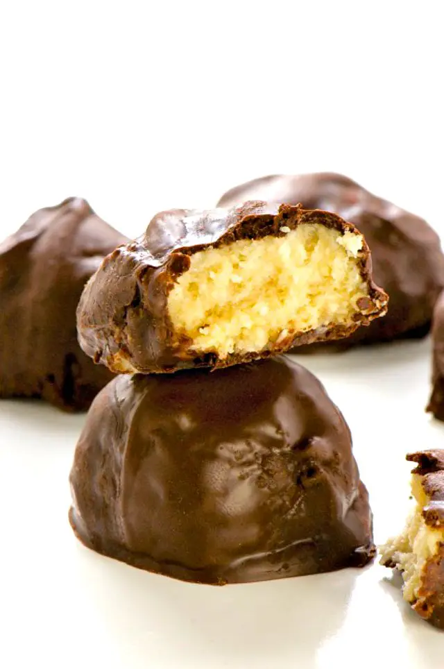 Two almond joy bites sit on top of each other. A bite has been taken out of the top one to reveal lots of coconut inside.