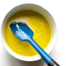 Looking down into a bowl with batter in it and a blue spatula.