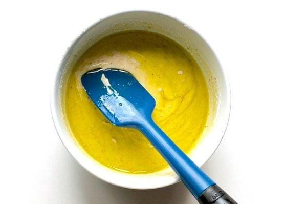 Looking down into a bowl with batter in it and a blue spatula.