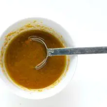 A dark sauce is in a bowl with a spoon.
