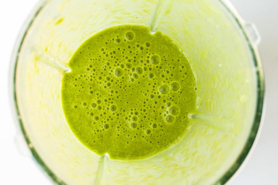 A close-up look at freshly blended spinach and other ingredients in a blender.