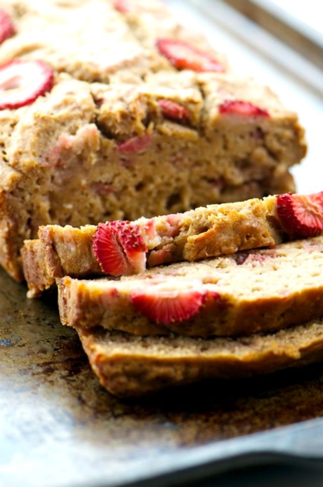 A closeup of banana bread with sliced strawberries on top.