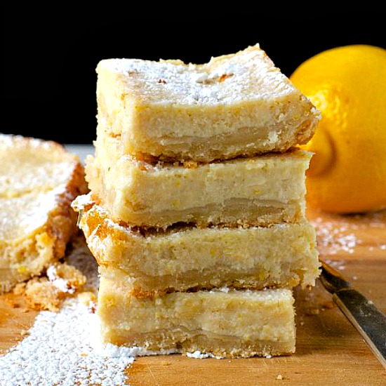 A stack of lemon bars on a wooden tray.