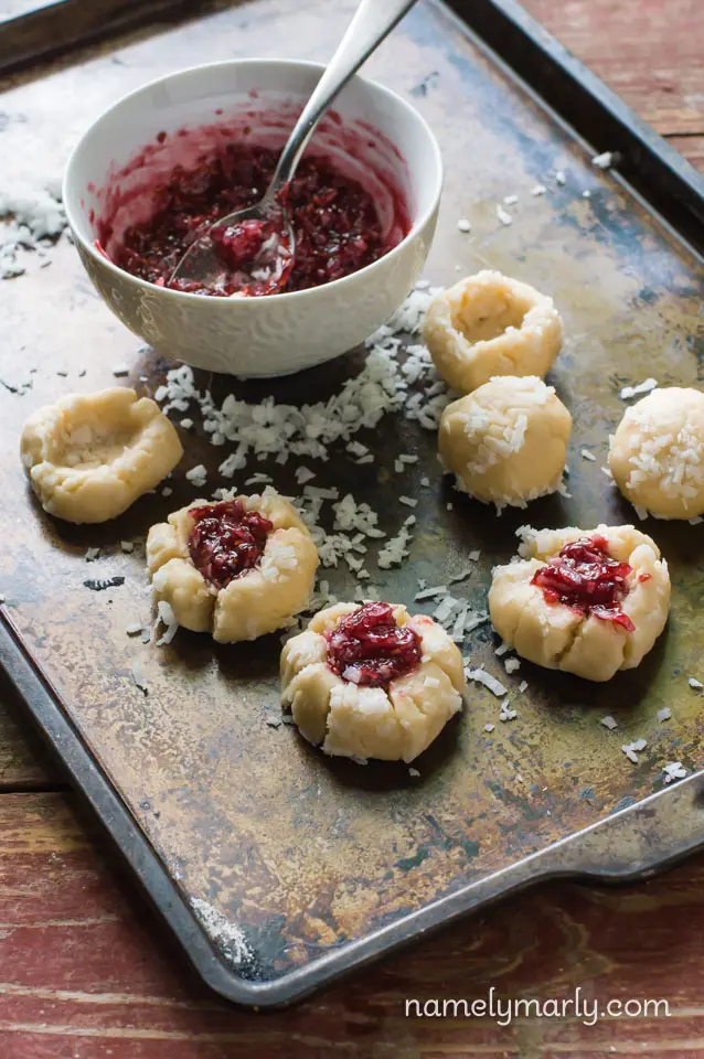 Raspberry sauce is placed in a thumbprint hole in the unbaked cookie balls.