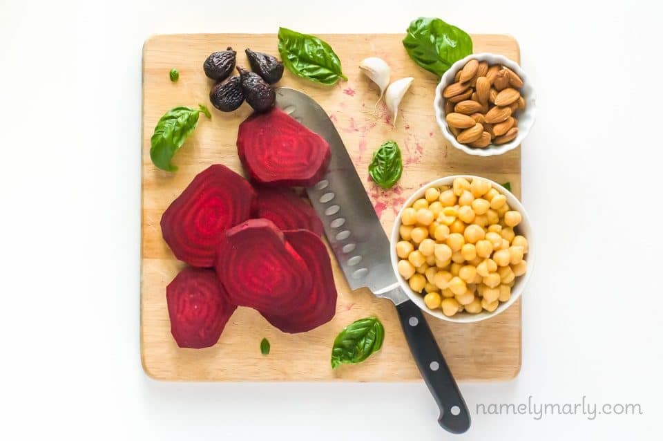 The ingredients in place for Roasted Beet Hummus on a cutting board, such as sliced beets, chickpeas, and more.