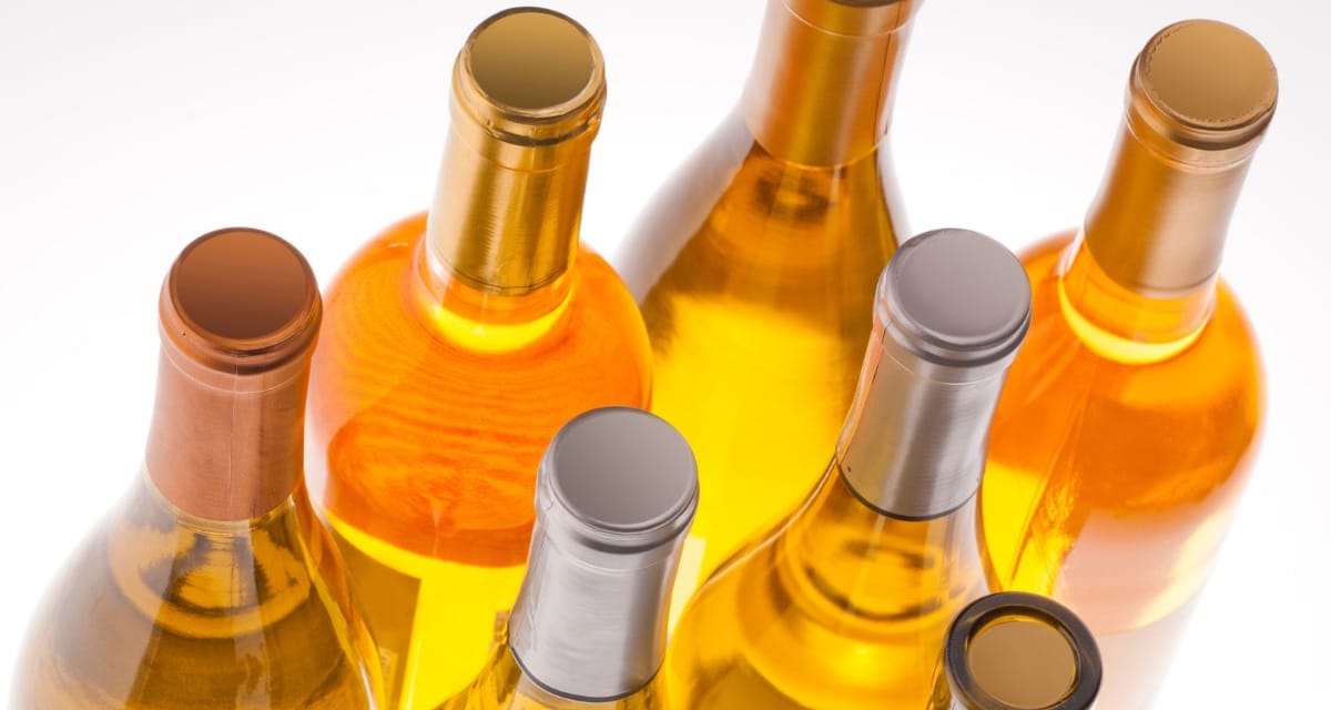 Looking down on several bottles of white wine, several with different labels and tops.