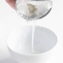 a can of coconut milk being drained into a bowl