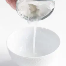 a can of coconut milk being drained into a bowl