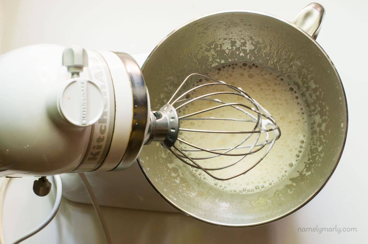 A stand mixer holds ingredients to make vegan meringue.