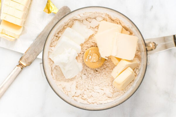 A food processor jar with ingredients to make a vegan pie crust