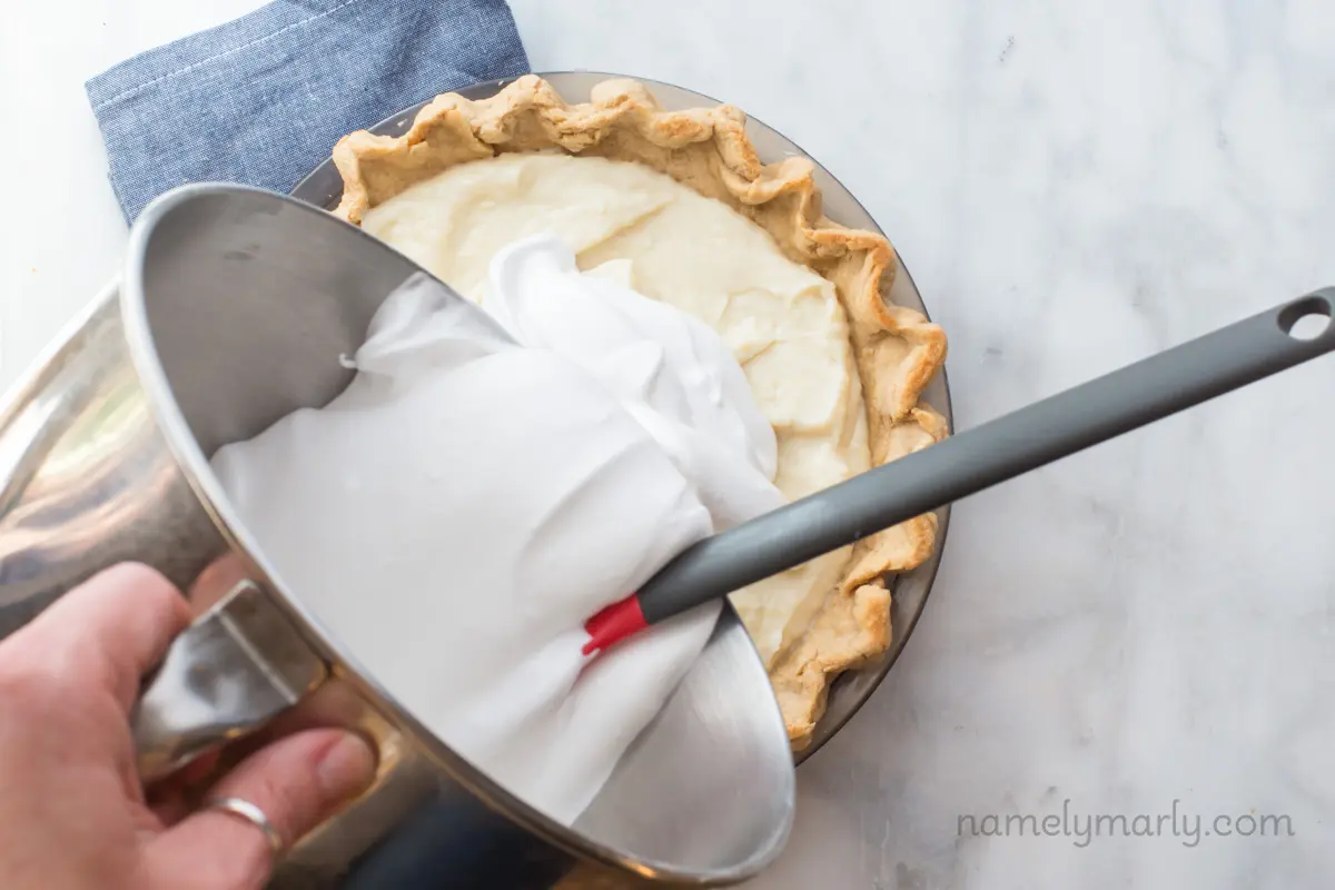 Meringue is being poured over a cream pie.