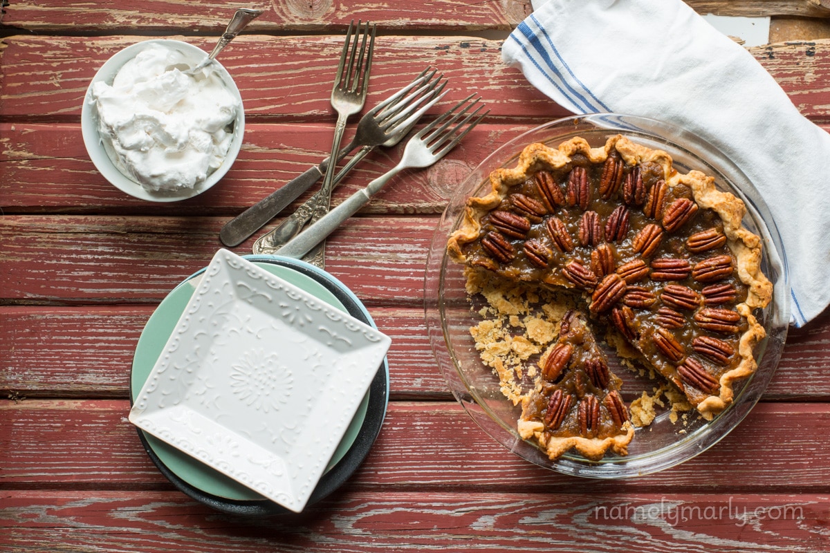 Looking down on a pecan pie with a slice cut out and ready to be served. vegan whipped cream.