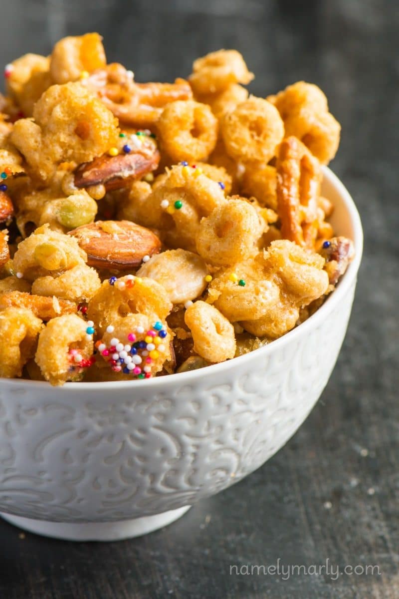 A bowl of Cheerio caramel snack mix sits on a table top.