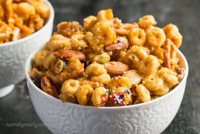 One bowl of Cheerio snack mix sits in front of another bowl. 