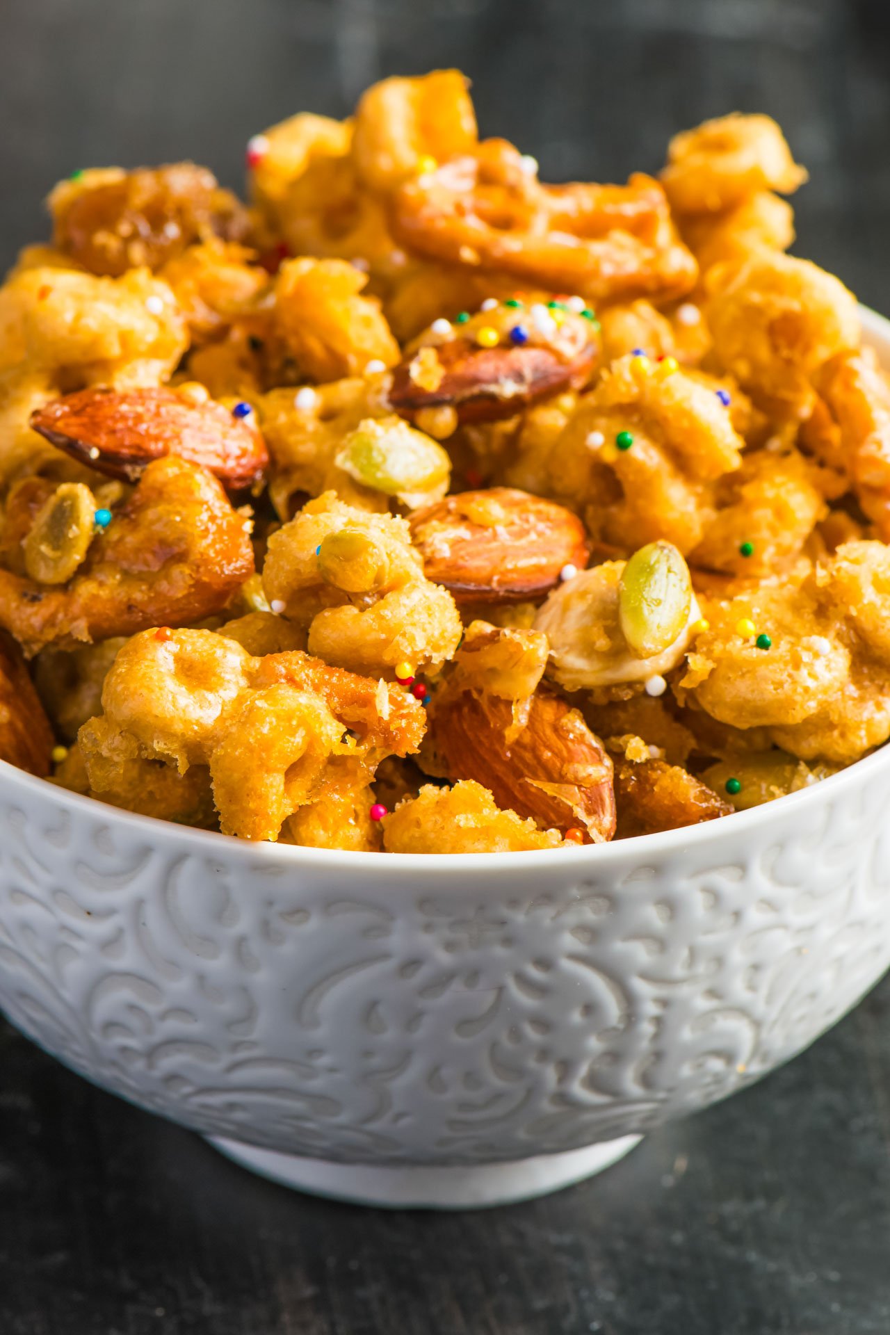 A closeup of caramel snack mix in a bowl.