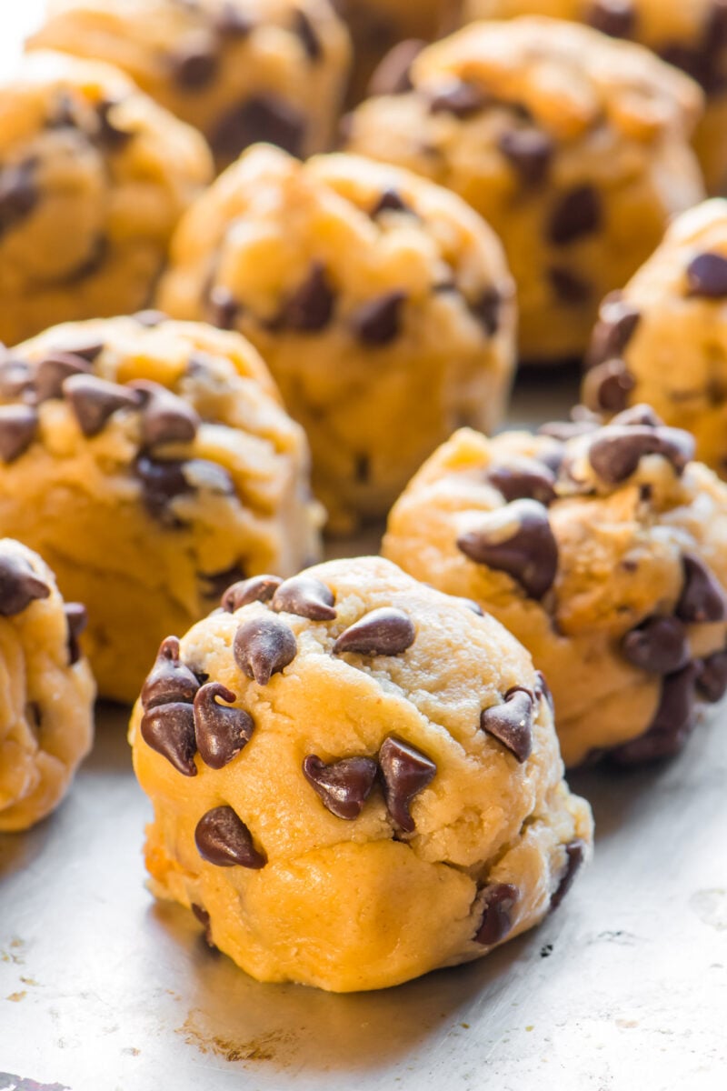 Several frozen cookie dough balls on a baking sheet