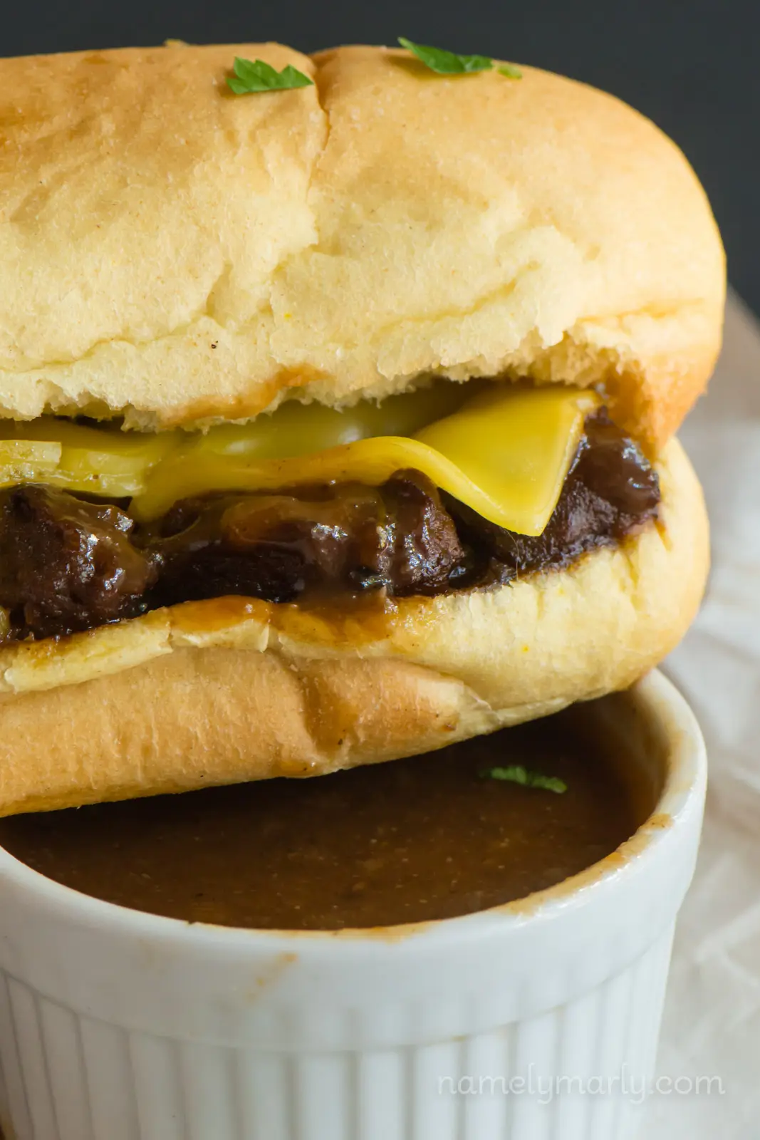 An au jus sandwich sits on a small bowl of gravy.