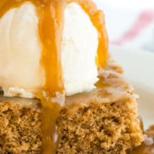 A slice of vegan cinnamon roll poke cake has a scoop of ice cream on the top and is drizzled with caramel sauce.