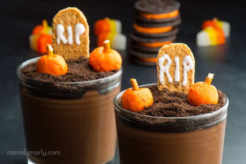 Cups of vegan pudding are decorated for Halloween with orange filled Oreos in the background.