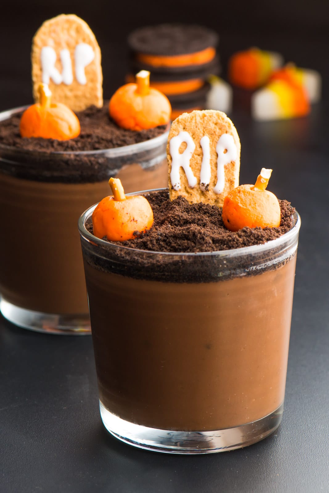 A vegan Halloween pudding cup has candy pumpkins on the top with a graham cracker that reads, "RIP."