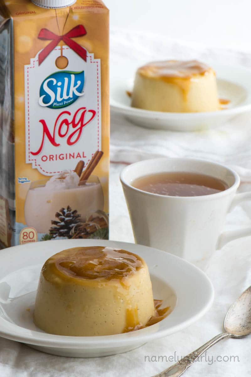 Two plates of vegan flan with a cup of tea and a container of Silk dairy-free Nog.