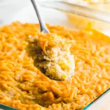 A spoonful of vegan corn casserole hovers over the rest of the casserole dish.