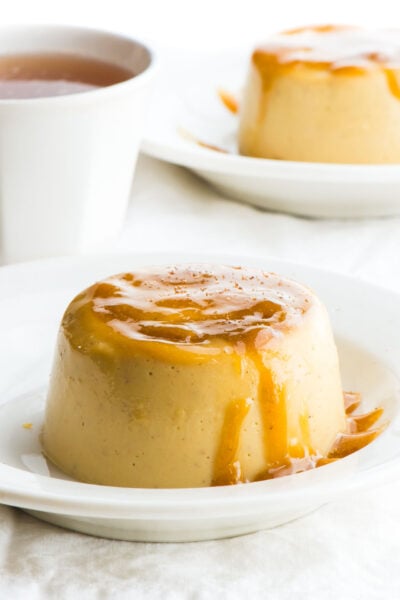 A closeup of vegan eggnog flan with caramel topping. Another plate is behind it.