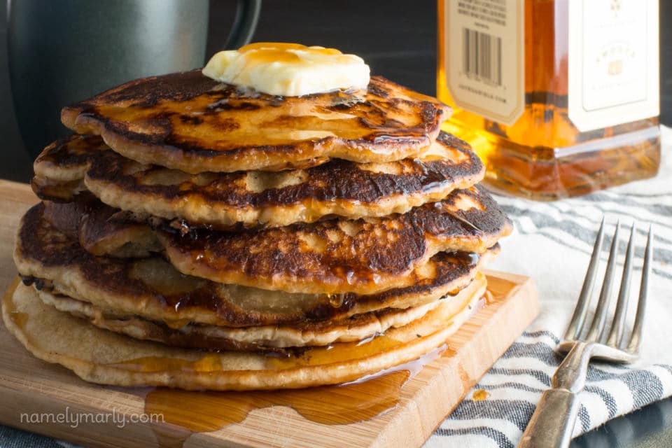 A stack of vegan whiskey pancakes with melted butter on top with a fork beside it.