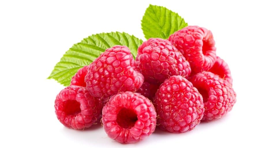 A mound of fresh raspberries has two leaves from the bush behind it.