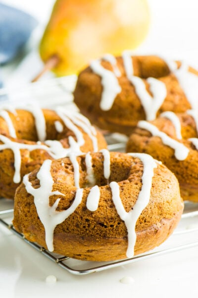 Several Vegan Ginger Pear Donuts sit on a baking rack.