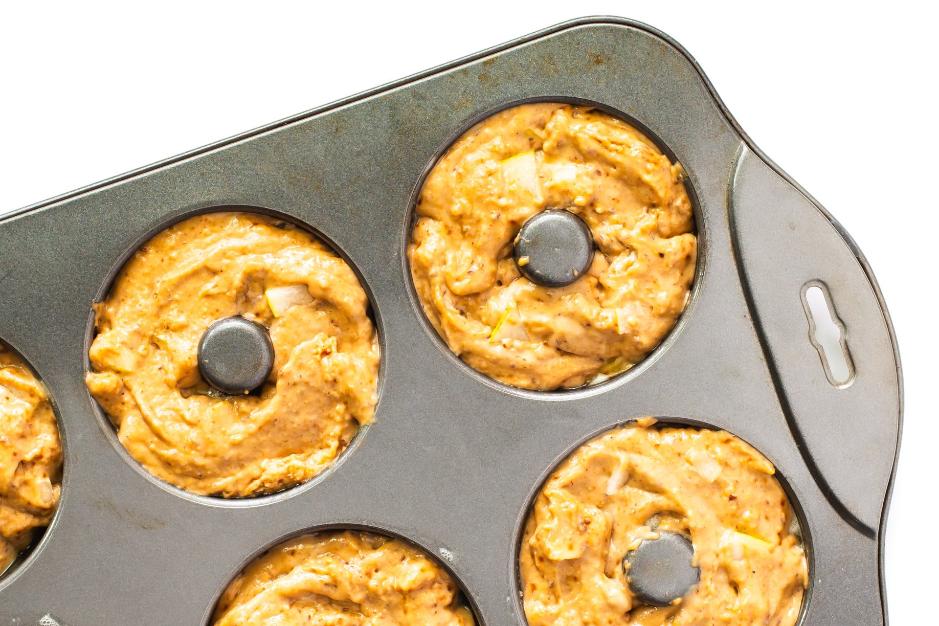 A donut pan has compartments full of batter.