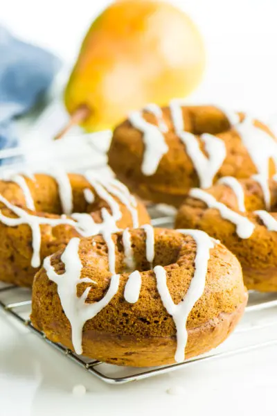 Several Vegan Ginger Pear Donuts sit on a baking rack.