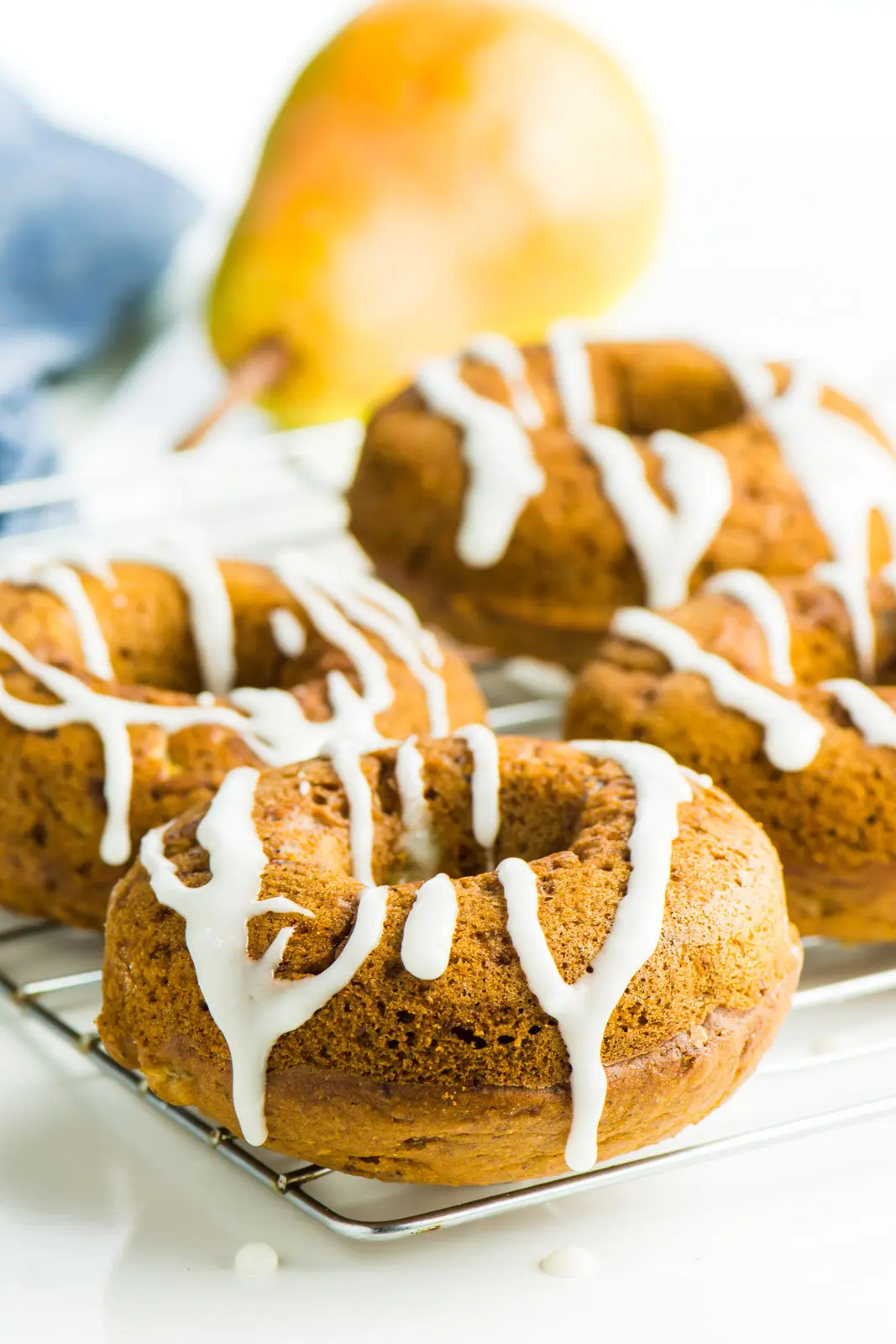 Several ginger donuts sit on a baking rack. They have icing drizzled over the top.